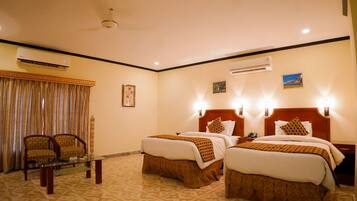 A hotel room with two beds, a chair, an air conditioning unit, and a patterned floor.
