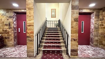 A staircase with a red carpet leading to a landing with a framed picture.
