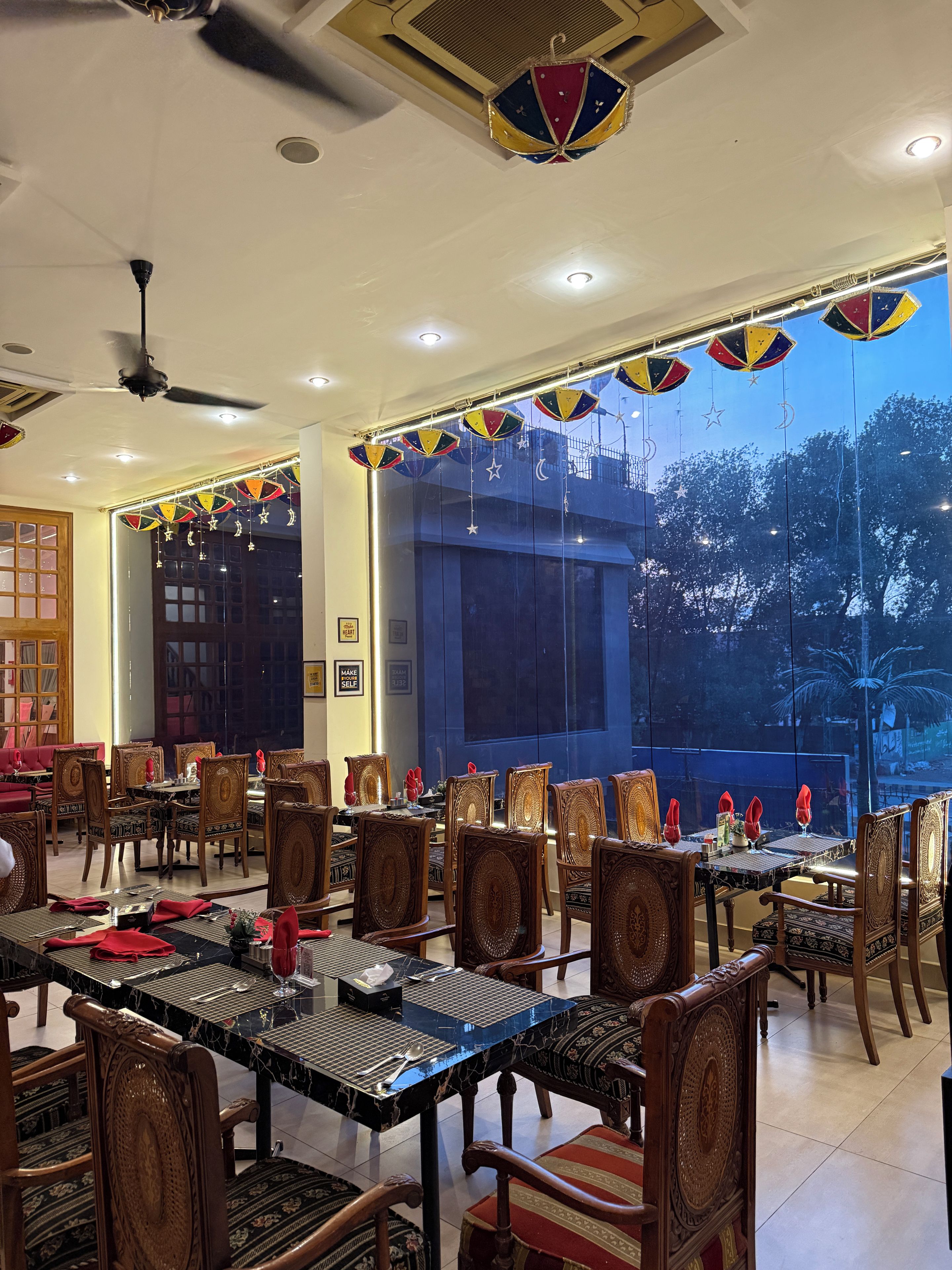 A dining area with tables and chairs, a ceiling fan, and decorative hanging ornaments.