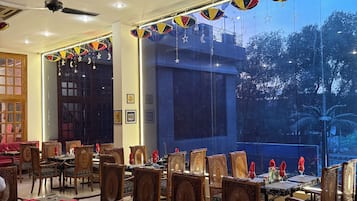 A dining area with tables and chairs, a ceiling fan, and decorative hanging ornaments.