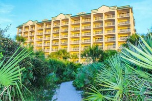 A multi-story hotel with balconies, surrounded by tropical vegetation. - Oceanfront 2BR Cocoa Beach | Balcony | Sleeps 5 (Cocoa Beach)