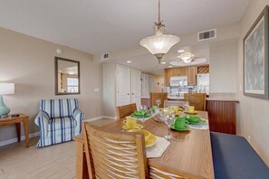 A dining area with a wooden table, chairs, and a chandelier. - Oceanfront 2BR Cocoa Beach | Balcony | Sleeps 5 (Cocoa Beach)