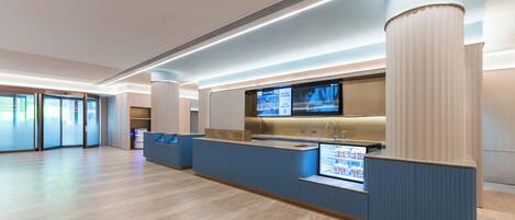 A modern reception area with a counter, a television screen, and a large window.