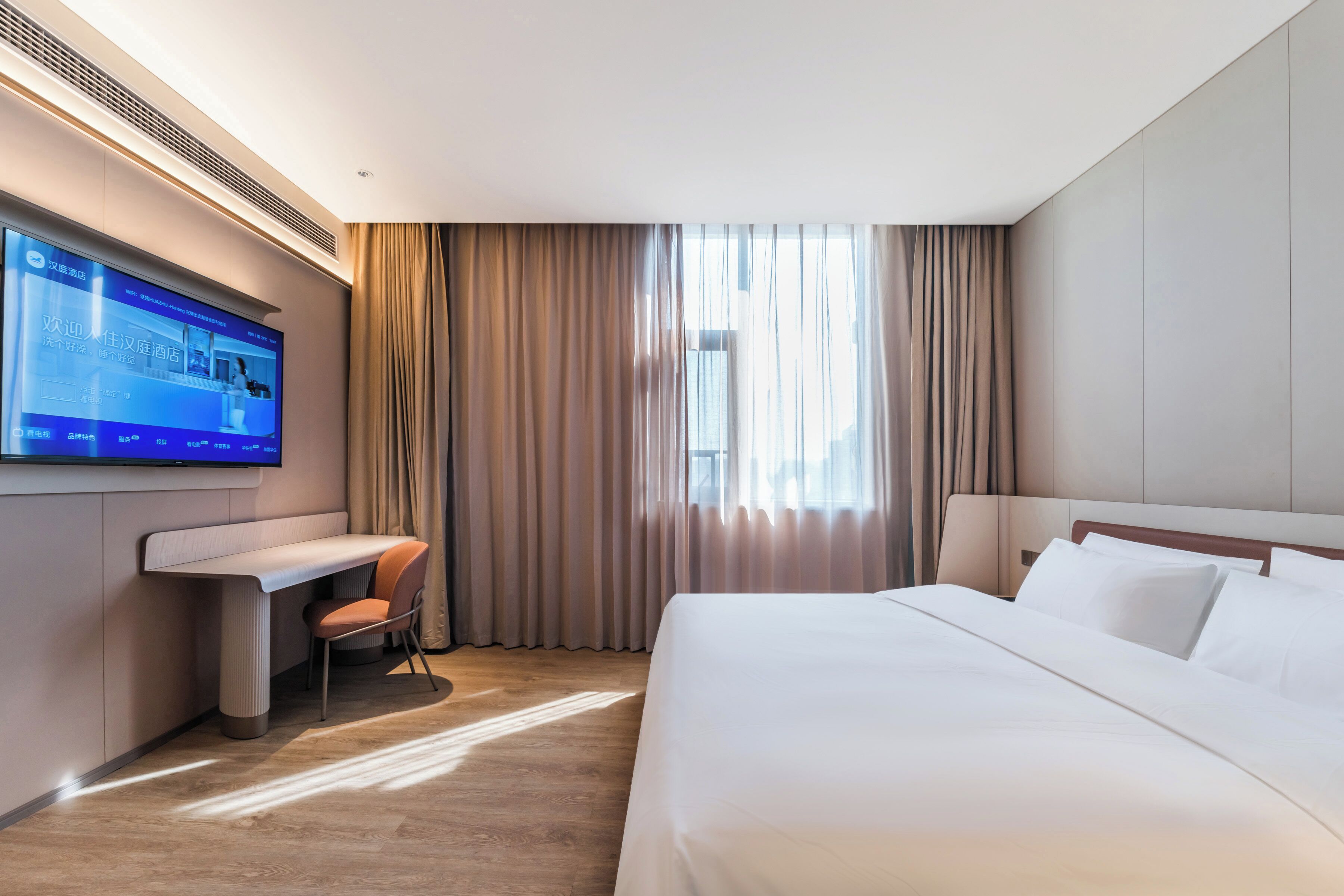 Habitación de hotel con cama, escritorio, silla, televisor y ventana con cortinas.