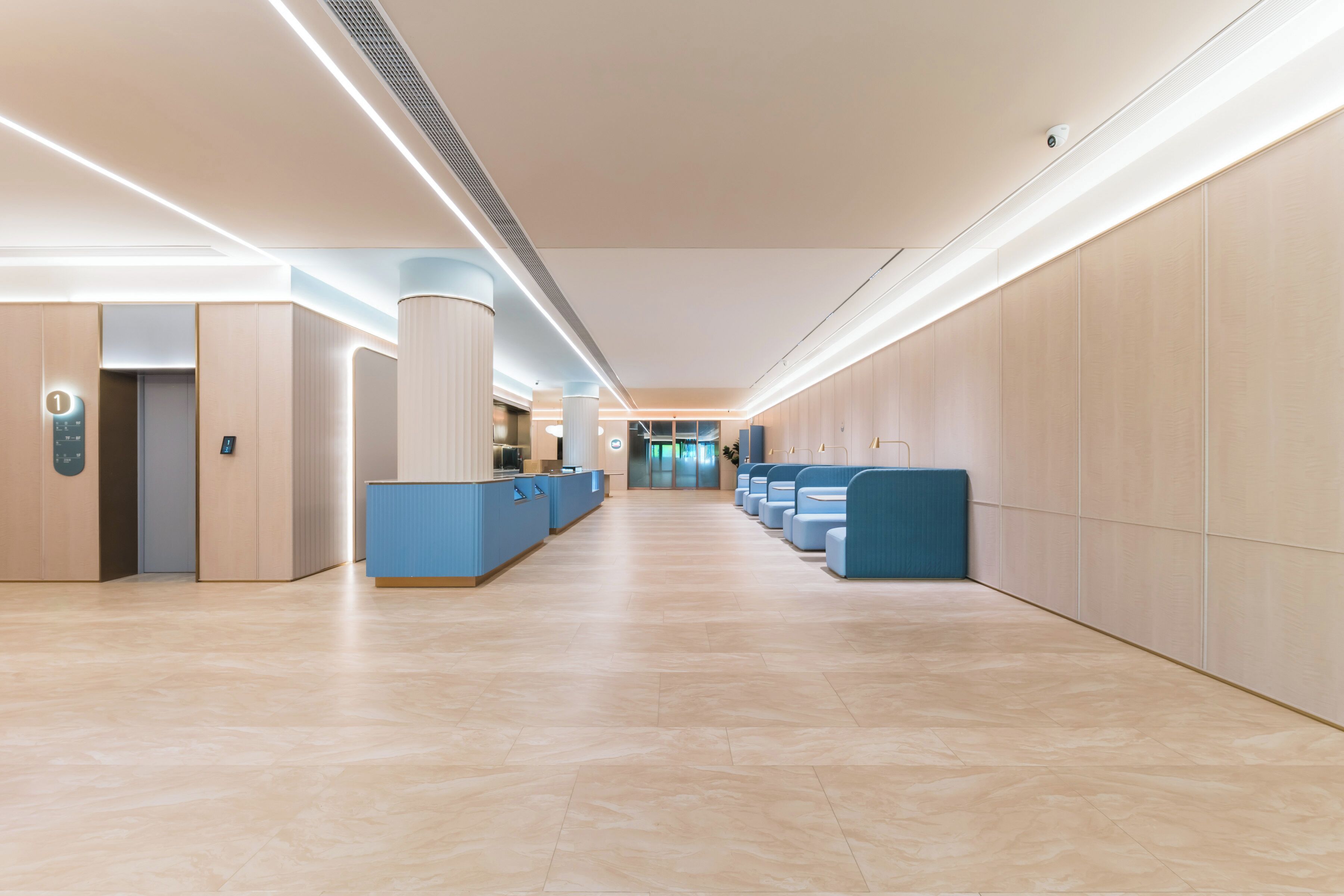 Un hall d’hôtel moderne comprenant un comptoir d’accueil, un espace salon et une vue dégagée sur l’ascenseur.