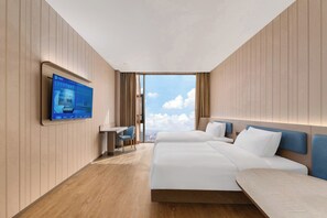 Habitación de hotel con una cama grande, un escritorio, una silla y un televisor en la pared.
