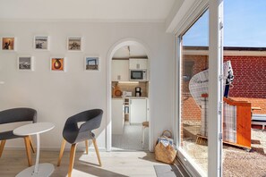 A modern interior with a dining area, kitchen, and a view of the outside. - Kyra - Westerland (Westerland)