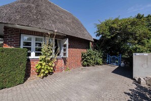A brick house with a thatched roof, a paved driveway, and a blue gate. - Kyra - Westerland (Westerland)
