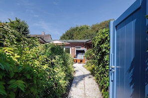 A pathway leading to a house with a brick exterior and a small porch area. - Kyra - Westerland (Westerland)