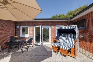 A patio with a table, chairs, a striped sofa, and an umbrella. - Kyra - Westerland (Westerland)