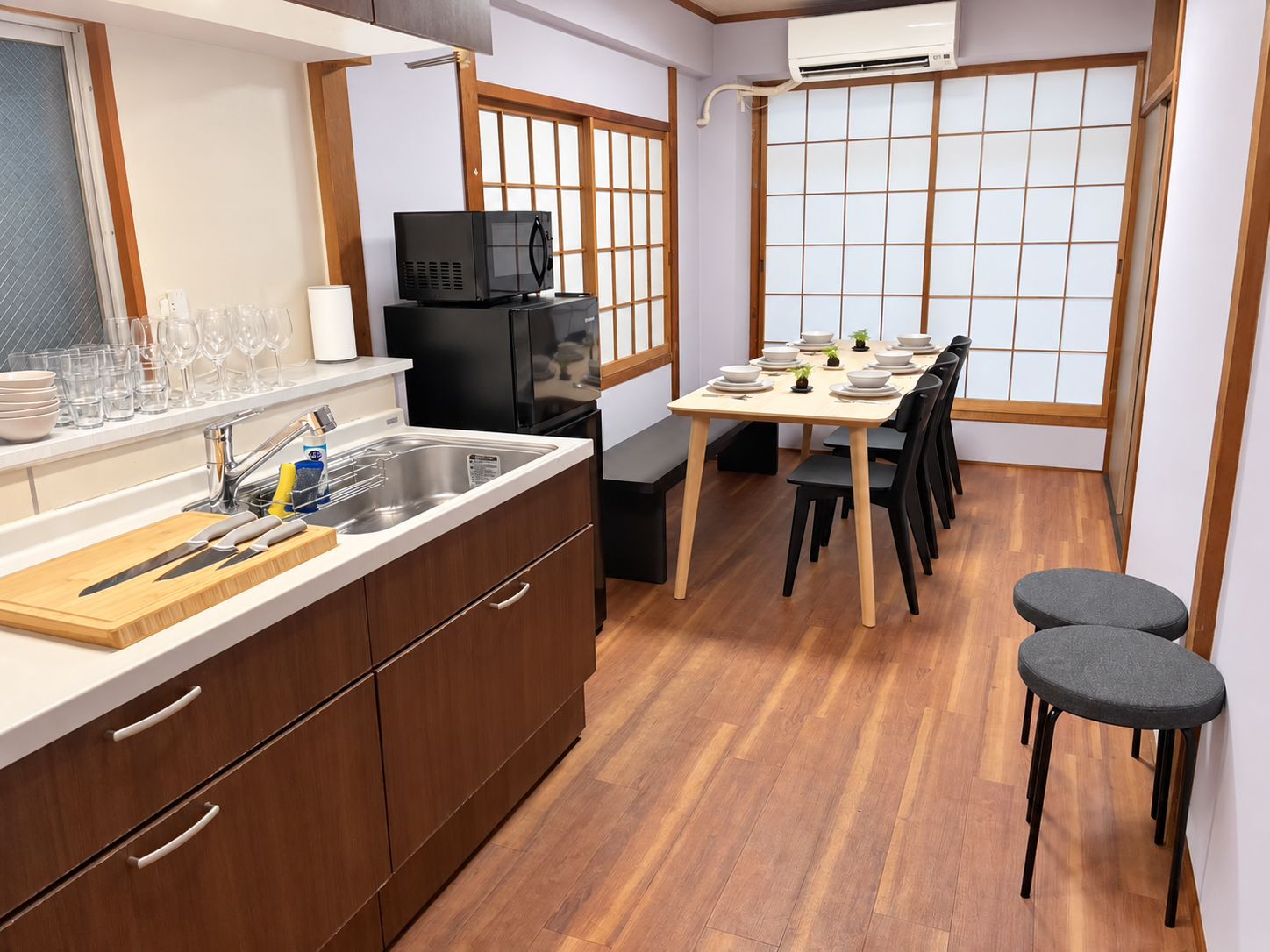 A compact kitchen with a sink, microwave, and dining area with a table set for four.