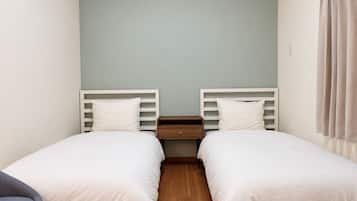 A twin room with two single beds, a wooden nightstand, and a light-colored wall.