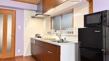 A compact kitchen with wooden cabinets, a stainless steel sink, and a black refrigerator.