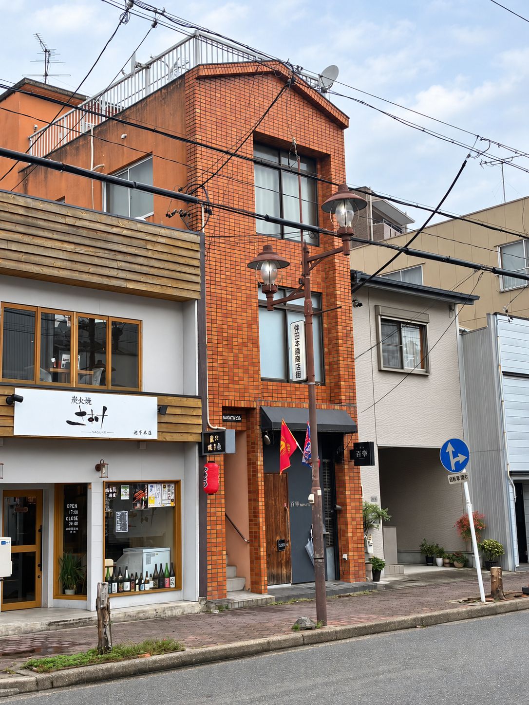 A multi-story building with a brick facade, a storefront with a sign, and a street sign indicating a one-way street.