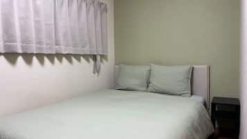 A single bed with a headboard, a nightstand, and a curtain.