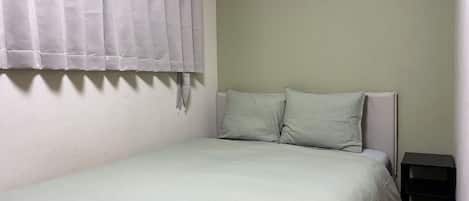 A single bed with a headboard, a nightstand, and a curtain.