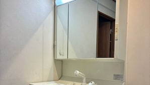 A bathroom with a white sink, a mirror, and dark wooden cabinets. - The House Nagoya 5DK (Nakata, Chikusa-ku, Nagoya-shi)