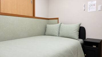Una cama individual con cabecera, mesita de noche y un interruptor de luz en la pared.