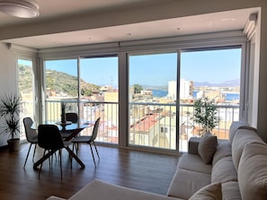 A spacious living room with a balcony, large windows, a dining area, and a sofa. - A LUXURIOUS AND COMFORTABLE OASIS WITH OCEAN VIEWS (Aguilas)