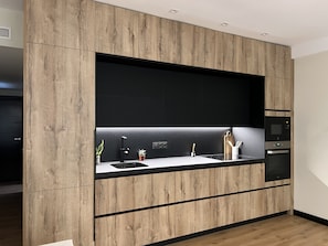 A modern kitchen with wooden cabinetry, a black countertop, and built-in appliances. - A LUXURIOUS AND COMFORTABLE OASIS WITH OCEAN VIEWS (Aguilas)
