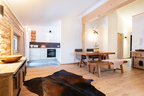 A modern kitchen with white cabinets, a wooden dining table, and a leather rug. - Watzmann Vacation Rental, 74 square meters (Schönau am Königssee)