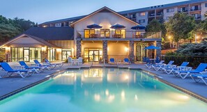 Un hotel con piscina, lettini e posti a sedere all'aperto.