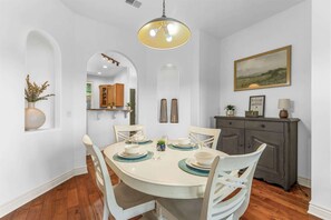 A dining area with a round table, white chairs, and a dark wooden cabinet. - Silver Dollar Awesome - 2bdr (Branson)