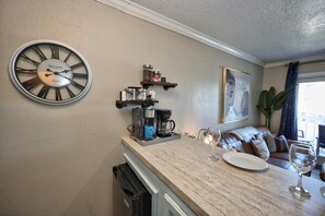 Eine Küche mit einer großen Wanduhr, einer Kaffeemaschine und Regalen mit Gläsern.