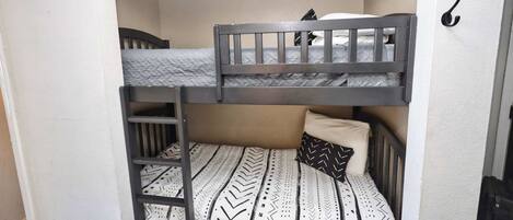 A bunk bed with a ladder, a pillow, and a hook on the wall.