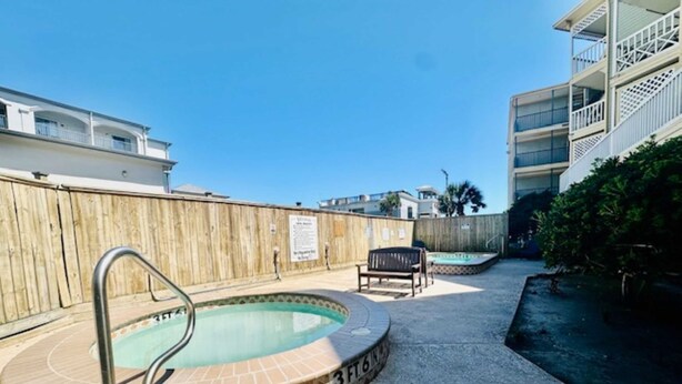 A swimming pool with a metal ladder, a wooden fence, and a bench. - Seawall Serenity - Amenities (Galveston)