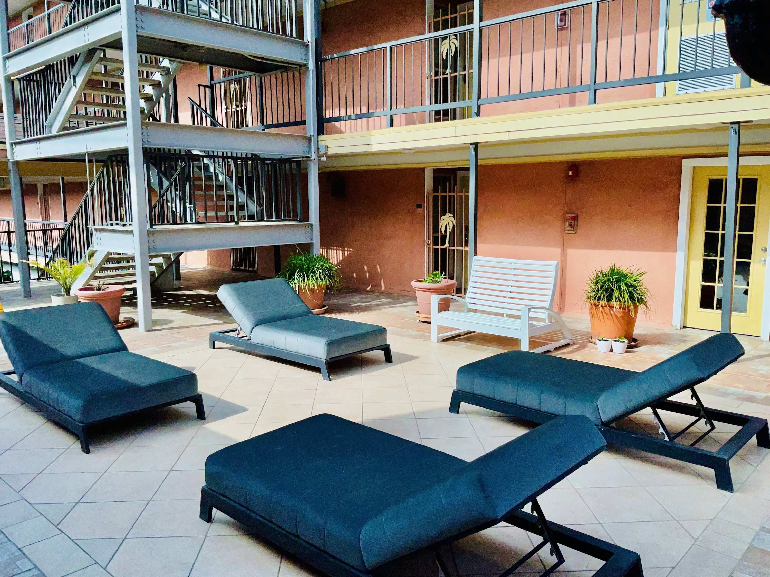 A multi-level outdoor area with a pool, lounge chairs, and potted plants.