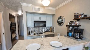 A modern kitchen with a central island, a microwave, and a coffee maker. - Seawall Serenity - Amenities (Galveston)