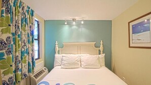 Un dormitori amb un llit, una finestra amb cortines, un quadre penjat a la paret i una làmpada al sostre.