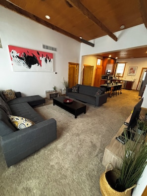 A living room with a sectional sofa, a coffee table, and a painting on the wall.