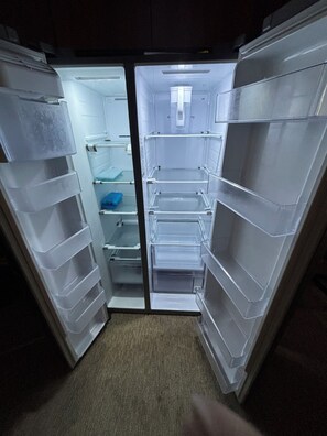 An open refrigerator with multiple shelves and drawers, a small window, and a light source above.