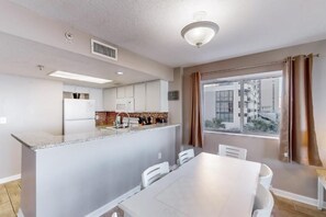 Una cocina moderna con armarios blancos, una isla central y un comedor con mesa y sillas.