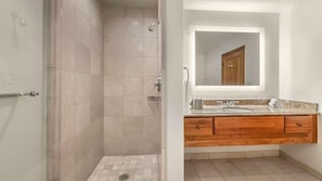 A bathroom with a shower, vanity, and a mirror.