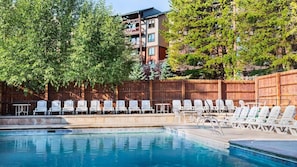 A swimming pool with lounge chairs and a wooden fence.