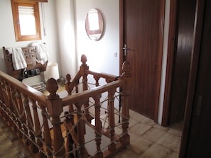 A wooden staircase with a handrail, a wooden door, a mirror, and a window with blinds.