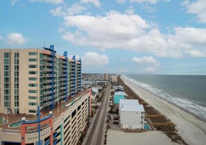 A multi-story hotel with balconies, a pool area, and a beach view. - Oceanfront 2BR | Balcony, Pools & Lazy River (North Myrtle Beach)