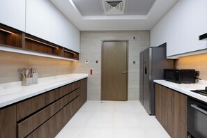 Eine moderne Küche mit Holzschränken, einem Edelstahlkühlschrank und einer Mikrowelle.