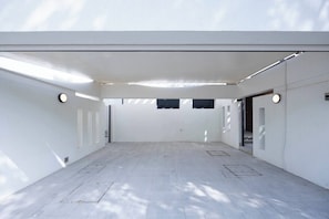 Ein leerer Raum mit hoher Decke, Dachfenstern und einer schlichten weißen Wand.