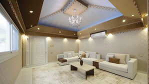Uma sala de estar ampla com um sofá branco grande, uma mesa de centro e um lustre.