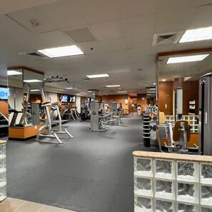 Una palestra con diverse attrezzature per esercizi, specchi e pavimento piastrellato.