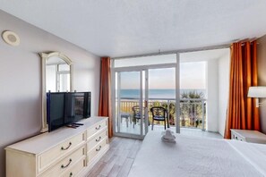 Een hotelkamer met balkon, televisie, bed en dressoir.