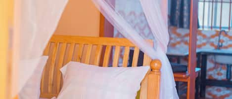 A bed with a wooden frame and white bedding, a canopy, and a wooden floor.