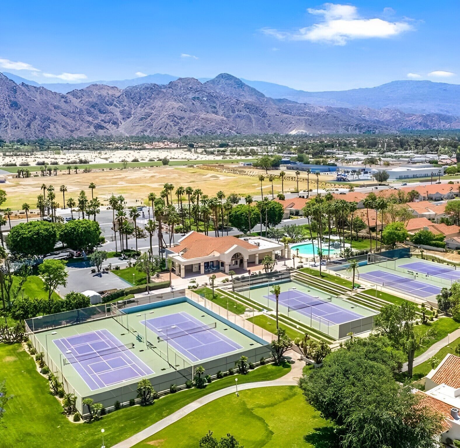 Complejo de canchas de tenis con varias pistas, rodeado de zonas verdes y edificios residenciales.