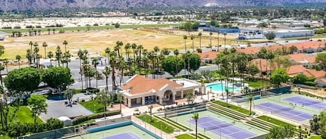 Complejo de canchas de tenis con varias pistas, rodeado de zonas verdes y edificios residenciales.