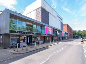A modern building with a sign reading "Theatre Royal" and "Passionate Enlightening Revealing Fascinating Outstanding Romantic." - A comfortable two bedroom terrace house in NR2, sleeping four across two rooms, one with en suite shower-room. Free on street parking and log burner. (Norwich)