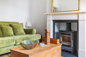 Ein Wohnzimmer mit einem grünen Sofa, einem Kamin und einem Holztisch mit einer Schüssel.